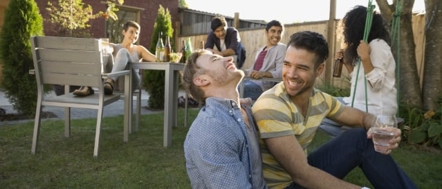 Group of friends enjoying drinks and laughs outside in the back yard.