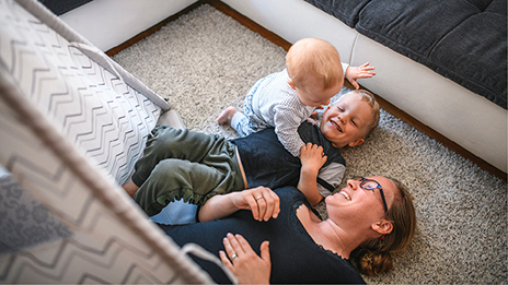 A new mother playing with her young toddler and baby.